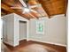 Well-lit bedroom featuring a beamed ceiling with fan, wood floors, closet, and views to nature from the window at 5642 Dorsett Shoals Rd, Douglasville, GA 30135