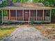 Charming log cabin featuring a cozy front porch and stone chimney at 5642 Dorsett Shoals Rd, Douglasville, GA 30135