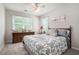 This comfortable bedroom has neutral carpet, a ceiling fan, and a large window that lets in ample sunlight at 1655 Peachcrest Dr, Lawrenceville, GA 30043