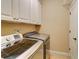 Functional laundry room featuring side-by-side washer and dryer with white cabinets above and a white door at 805 Cog Hl, Mcdonough, GA 30253