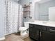 Stylish bathroom features black vanity, open shelving and shower with patterned curtain at 132 Berkleigh Trails Dr, Hiram, GA 30141