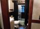 Cozy bathroom featuring black tile accents, toilet, shower with glass doors, and dark floral wallpaper at 2765 Rollingwood Se Ln, Atlanta, GA 30316