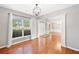 Open floor plan with hardwood floors, neutral walls, and chandelier illuminated by natural light at 3850 Calomel Dr, Cumming, GA 30040
