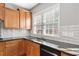 Kitchen with wood cabinets, granite countertops, tiled backsplash and stainless steel sink beneath a bright window at 3850 Calomel Dr, Cumming, GA 30040