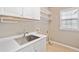 Practical laundry room with white cabinets, shelving, and a stainless steel sink at 3850 Calomel Dr, Cumming, GA 30040