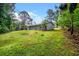 View of the rear of the home and treed back yard with a sloping grade at 3645 Shrewsbury Ct, Snellville, GA 30039