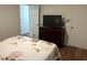 Bedroom features a dark wood dresser with TV, a floral bedspread, wood floors, and a view of a closet at 4325 Dawning Ln, Douglasville, GA 30135