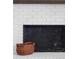 Close-up of white brick fireplace with dark firebox and decorative basket on the hearth at 5070 Hensley Dr, Atlanta, GA 30338