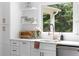 Bright, all-white kitchen featuring a stainless steel sink, copper faucet, and view to the backyard at 5070 Hensley Dr, Atlanta, GA 30338