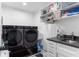 Modern laundry room with a black washer and dryer, a sink, and built-in shelves at 5070 Hensley Dr, Atlanta, GA 30338