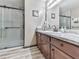 Modern bathroom with wood tile floors, wood cabinets, granite counters, a glass shower, and updated fixtures at 629 Silver Trace Ct, Woodstock, GA 30189