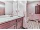 A charming bathroom with pink walls, a vanity, wood cabinet, black and white tile flooring, and a shower tub combo at 629 Silver Trace Ct, Woodstock, GA 30189