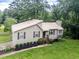 A house with a nice lawn featuring a metal roof, neutral siding, dark shutters, and stairs leading to the front door at 629 Silver Trace Ct, Woodstock, GA 30189