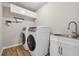 Well-lit laundry room with stainless sink, wood-look flooring, and side by side washer and dryer at 1820 Primrose Park Rd, Sugar Hill, GA 30518