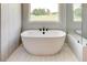 Bright window illuminates the elegant white standalone soaking tub, part of a luxurious main bathroom at 3063 Reserve Ct Sw, Conyers, GA 30094
