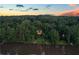 Distant aerial view of a home nestled in a lush forest by the lake at sunset at 132 Lakeshore Dr, Roswell, GA 30075