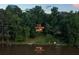 Scenic aerial view of lakefront property with a modern home surrounded by lush greenery at 132 Lakeshore Dr, Roswell, GA 30075