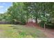 Picture of a backyard with lush green grass and mature trees, enclosed by a charming red fence at 2470 Hillvale Cir, Lithonia, GA 30058
