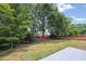 Expansive backyard with lush green grass and mature trees, enclosed by a charming red fence at 2470 Hillvale Cir, Lithonia, GA 30058