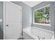 Bright bathroom boasts garden tub, large window, and white door at 2470 Hillvale Cir, Lithonia, GA 30058