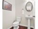 Cozy half bathroom features a pedestal sink, wood floors, decorative art, and neutral color scheme at 228 Stone Park Dr, Woodstock, GA 30188