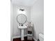Neat half bathroom featuring pedestal sink, round mirror, and modern fixtures at 50 Mount Vernon Cir, Atlanta, GA 30338
