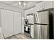 Compact kitchen featuring stainless steel appliances, white cabinets, and a double-door pantry at 830 Bonnie Glen Se Dr, Marietta, GA 30067