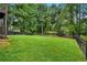 Grassy backyard with a black fence and mature trees for privacy at 230 Sheringham Dr, Roswell, GA 30076