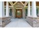 Close-up of a welcoming front porch featuring stone, white columns, and a double wooden front door at 7269 Tyree Rd, Winston, GA 30187