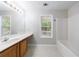 Bright bathroom with a window, a sink vanity with a mirror and lighting fixtures, and a white bathtub at 1830 Broadway St, Decatur, GA 30035