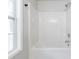 Close up view of a white bath tub and shower with a window for natural light in this bathroom at 1830 Broadway St, Decatur, GA 30035