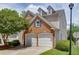 Two-car garage with brick facade and dormer windows, part of a charming townhome with a landscaped yard at 2421 Elkhorn Ter, Duluth, GA 30096