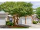 Brick townhome featuring a two-car garage, mature tree, and inviting blue front door at 2421 Elkhorn Ter, Duluth, GA 30096