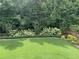 Landscaped backyard showcasing manicured lawn, blooming bushes, and a wooded backdrop at 6738 Brookfield Way, Douglasville, GA 30134