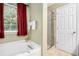 Bright bathroom featuring a tub with a window view and a glass-enclosed shower at 6738 Brookfield Way, Douglasville, GA 30134