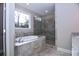 Elegant bathroom showcasing a soaking tub, glass-enclosed shower with stylish tiling, and vanity with granite countertop at 14 Berkten Ct, Hiram, GA 30141