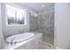 Luxurious bathroom featuring a soaking tub and a glass-enclosed shower with gray stone-look tile surround at 14 Berkten Ct, Hiram, GA 30141