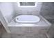 Close-up of a luxurious white soaking tub with modern fixtures and gray stone-look tile surround, creating a spa-like retreat at 14 Berkten Ct, Hiram, GA 30141