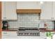 Kitchen with stainless steel stove, decorative backsplash, wooden countertops, and white cabinets at 1555 Steele Nw Dr, Atlanta, GA 30309