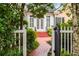 Charming front entrance with brick walkway, gated white fence, and beautifully landscaped greenery at 3786 Turnberry Ct, Duluth, GA 30096
