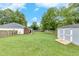 Backyard featuring lush green grass, a storage shed, and a covered patio area at 15 Echota Ne Rd, Cartersville, GA 30121