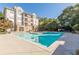 Bright pool area with condo building and mature landscaping on a sunny day at 220 Renaissance Ne Pkwy # 2220, Atlanta, GA 30308