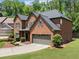 Side view of a charming two-story red brick home with a well-manicured lawn and a two-car garage at 5285 Winflow Way, Suwanee, GA 30024