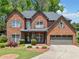 Charming two-story red brick home featuring a well-manicured lawn, gray shutters and a two-car garage at 5285 Winflow Way, Suwanee, GA 30024