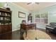 Home office showcasing dark wood desk and bookcase, natural light from window, and stylish decor at 5285 Winflow Way, Suwanee, GA 30024