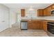 Traditional kitchen with wooden cabinets, stainless steel dishwasher and sink area with a view to the dining area at 5960 Castlegate Dr, Douglasville, GA 30135