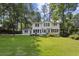 Expansive backyard featuring a lush lawn, white house, and mature trees offers ample space for recreation and relaxation at , Dunwoody, GA 30338