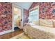Bright bedroom featuring floral wallpaper, hardwood floors, and ensuite bathroom access at 657 E Paces Ferry Ne Rd, Atlanta, GA 30305