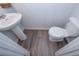 Powder room featuring a pedestal sink, toilet, and stylish wood-look laminate flooring at 110 Serendipity Way, Dallas, GA 30157