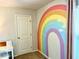 Rainbow accent wall in a cozy bedroom with a work desk and natural light from the window at 110 Serendipity Way, Dallas, GA 30157